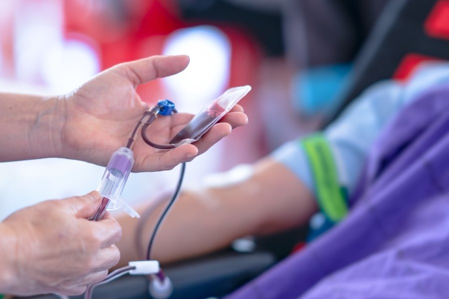 A close-up view of a medical professional conducting a blood test with a sample collection tube.Title: Stool Test Procedure at Synergy Hospital