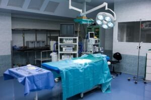 A well-equipped operating room with surgical tools laid out on a sterile table, illuminated by a bright surgical light.