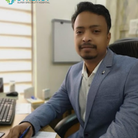 Professional Doctor at Synergy Super Speciality Hospital A professional male doctor at Synergy Super Speciality Hospital, seated at his desk, wearing a light blue blazer and white shirt, representing expertise and care.