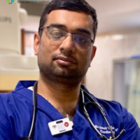 A professional male doctor wearing a stethoscope and blue scrubs at Synergy Super Speciality Hospital in Bhopal.