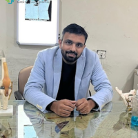 A healthcare professional seated at a desk with anatomical models, representing orthopedic or specialized medical care at Synergy Hospital in Bhopal.